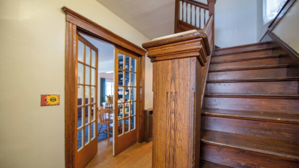 Eine Holztreppe mit Handlauf und einer Tür zu einem Zimmer mit Fenster.