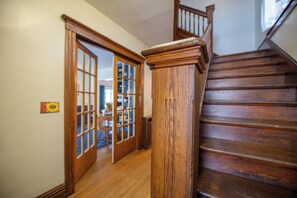 A wooden staircase with a handrail and a door leading to a room with a window.
