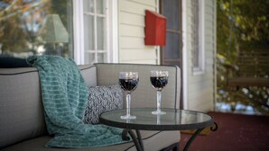 Ein Glastisch mit zwei Weingläsern auf einer Veranda.