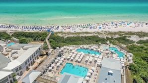 A resort with multiple swimming pools, beach umbrellas, and a view of the ocean.