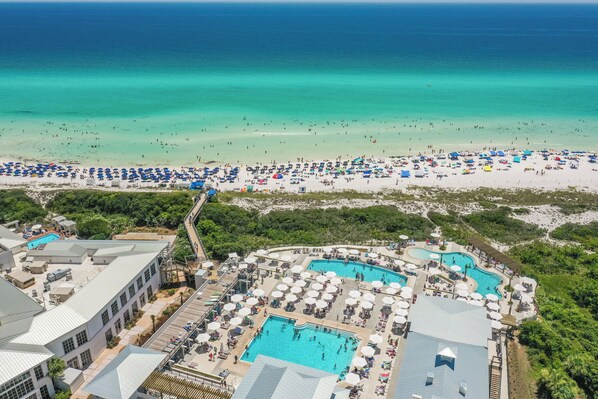 A resort with multiple swimming pools, beach umbrellas, and a view of the ocean.