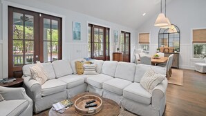 A spacious living room with a sectional sofa, a wooden coffee table, and a dining area with a table and chairs.