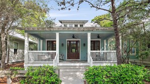 A two-story house with a porch, a front door, and a small front yard with a pathway.