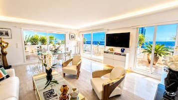 Een moderne woonkamer met een grote televisie, comfortabele zithoek en uitzicht op de oceaan.