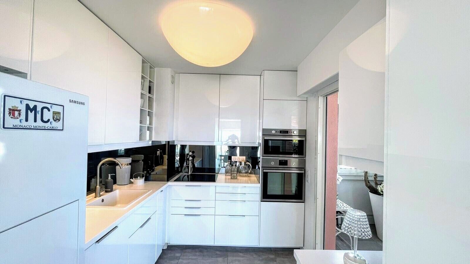 Een moderne keuken met witte kasten, een inbouwoven en een groot kookeiland met spoelbak.