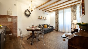 A modern living room with a dining table, clear chairs, a sofa, and a chandelier. - Casa Sorelle Flo - Flo Apartments (Firenze)