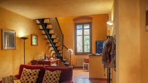A cozy living room with a red sofa, a staircase, and a dining area. - Cate Apartment - Flo Apartments (Firenze)