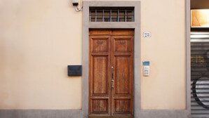 A wooden double door with a brass doorknob, a small window above it, and a number "28" on the wall to the right.