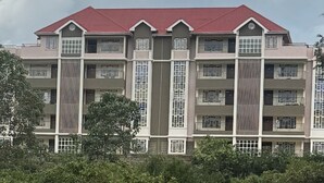 A multi-story building with a red roof, multiple balconies, and a central vertical feature. - Stylish fully furnished 2 bedroom  2 bath in Kitale 5 min from city center  (Kitale)