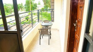 A balcony with a table and chairs, a view of greenery, and a wooden door. - Stylish fully furnished 2 bedroom  2 bath in Kitale 5 min from city center  (Kitale)