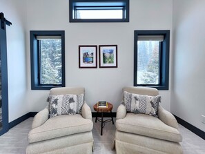 Una habitación con dos sillones, una mesita y dos cuadros en la pared.