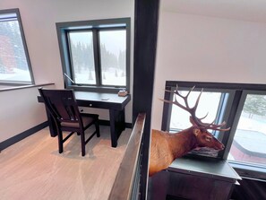 Una habitación con escritorio, silla y un ciervo disecado en la pared.