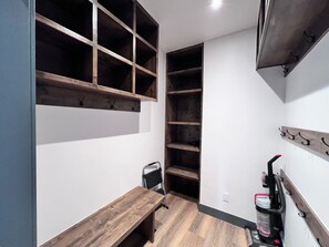 Habitación compacta con un banco de madera, estantes empotrados y un sistema de ganchos en la pared.