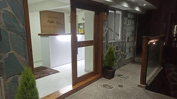 A reception area with a stone wall, a reception desk, and two potted plants. - Hotel Mont Blanc (Circasia)