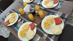 A table set with plates of food, including steak, rice, and fruit, and glasses of orange juice. - Hotel Mont Blanc (Circasia)