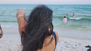 Escena de playa con gente en el agua y sobre la arena.