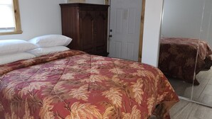Un dormitorio con cama, armario y espejo.
