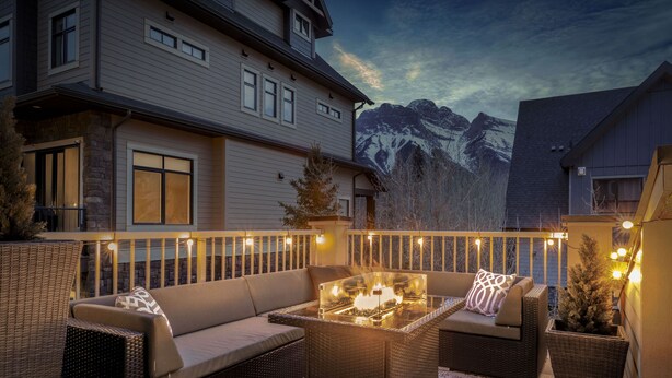 A patio with outdoor furniture, a glass-top table with a fire feature, and a view of mountains in the background. - Luxury 3BDRM - Chic Mountain Escape - BBQ/Fire Table (Canmore)