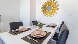 A dining table with placemats, bowls, and a potted plant. - The Midas Touch | Rooftop Pool & Free Parking (Darwin City)