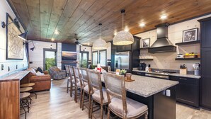 Une cuisine moderne dotée d’un îlot central, d’un plafond en bois et de luminaires suspendus.