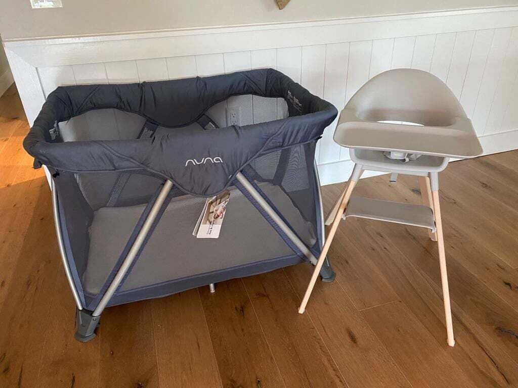 Un sofá cama convertible con dosel, una mesita pequeña y una silla en una habitación con suelo de madera y paredes blancas.