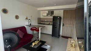A modern living room with a red sofa, a black coffee table, and a TV mounted on the wall.