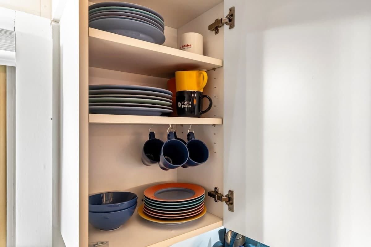 Un meuble de cuisine doté d’étagères où sont rangées des assiettes, des bols et des tasses.