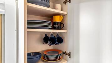 Un meuble de cuisine doté d’étagères où sont rangées des assiettes, des bols et des tasses.
