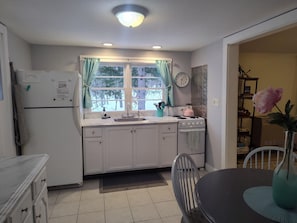 A kitchen with white cabinets, a sink, a stove, and a window with curtains. - Berkshires! Dog & Family Friendly, Hot Tub, Hiking, Lakes-Swimming, Canoeing (Becket)
