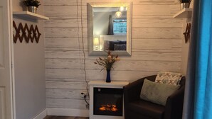 Una sala de estar con chimenea, un sofá, una alfombra y un espejo en la pared.
