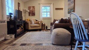 Una sala de estar con ventilador de techo, televisor, sofá, sillón y alfombra.