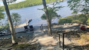 A wooden staircase leading to a dock with lounge chairs and a red chair by the water. - Lakefront Retreat with Private Dock and Hot Tub (Lackawaxen)