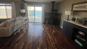 A cozy living room with a fireplace, a dining area, and a view of the lake. - Lake Life is for Everyone  (Maple Lake)