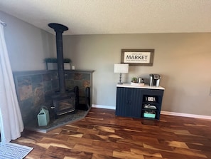 A living room with a stone fireplace, a clock, and a sign that reads "Maple Lake Market".