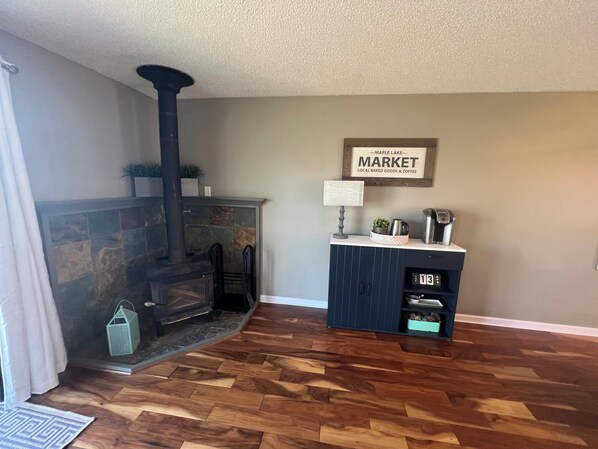 A living room with a stone fireplace, a clock, and a sign that reads "Maple Lake Market".