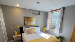 A bedroom with a bed, bedside tables, a window with curtains, a plant, and a painting on the wall. - Lake Life is for Everyone  (Maple Lake)