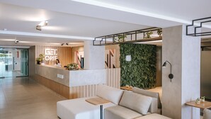 Uma área de recepção moderna com um letreiro 'GET LOVE', balcão de atendimento, parede verde e área de estar com sofá e uma mesa pequena.