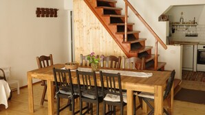 Una mesa de comedor de madera con sillas, una escalera y una zona de cocina.