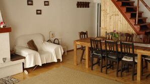 Una sala de estar acogedora con una mesa de comedor de madera, sillas, un sofá y una escalera.