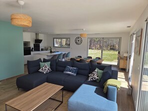 A modern living room with a sectional sofa, a wooden coffee table, and a dining area with a table and chairs.