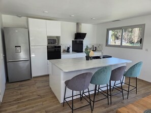 A modern kitchen with a built-in island, stainless steel appliances, and bar stools.
