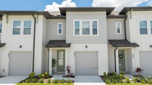 A row of townhouses with white siding, green doors, and numbered garage doors. - Gorgeous 3Bd Close To Disney @ Festival Resort 661 (Davenport)