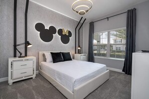 A modern bedroom with a large bed, two nightstands, a dresser, and Mickey Mouse wall art. - Gorgeous 4Bd W/ Pool & Waterpark @ Storey Lake 4836M (Kissimmee)