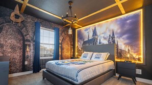 A bedroom with a large bed, a brick wall, a window with curtains, a nightstand, and a wall-mounted lamp. - Gorgeous 4Bd W/ Pool & Waterpark @ Storey Lake 4836M (Kissimmee)