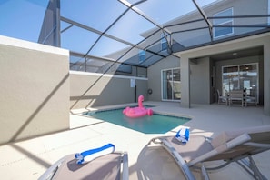 A rooftop pool area with lounge chairs and a pink flamingo float.
