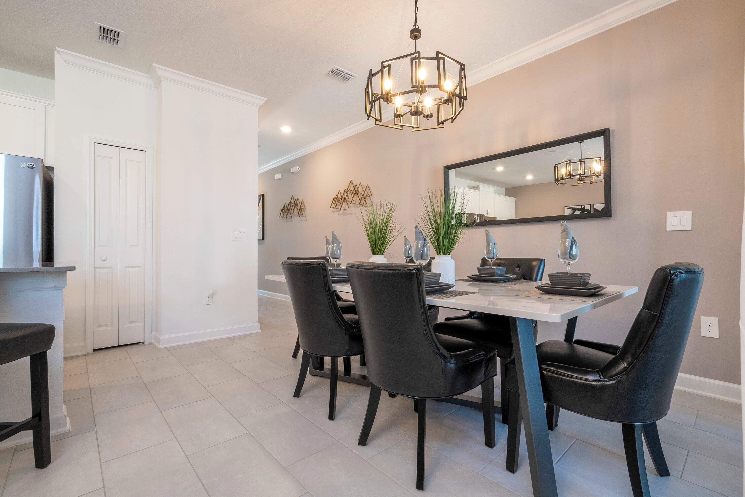 Un espace repas moderne avec une table blanche, des chaises noires et un lustre.