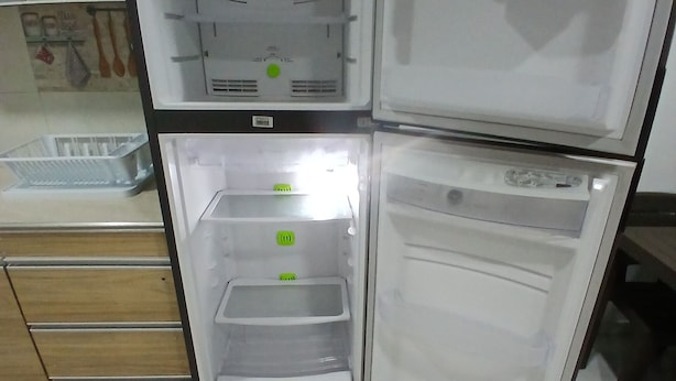Une cuisine équipée d’un réfrigérateur encastré, d’un plan de travail en bois et d’un sol carrelé.