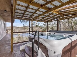Un jacuzzi bajo una pérgola de madera con vistas a un paisaje natural.