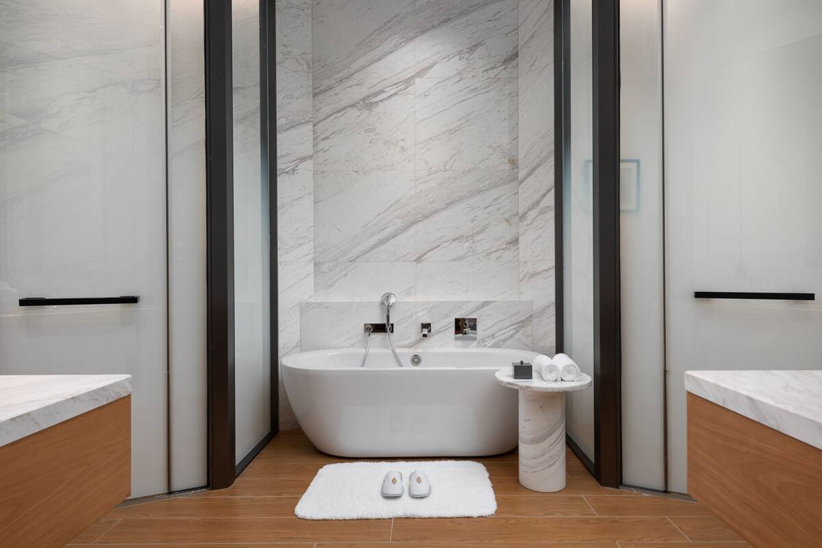 Une salle de bain moderne avec une baignoire sur pieds, un petit lavabo et un porte-serviettes.