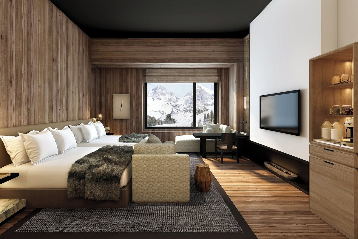 A modern bedroom with a large bed, a desk, and a television.